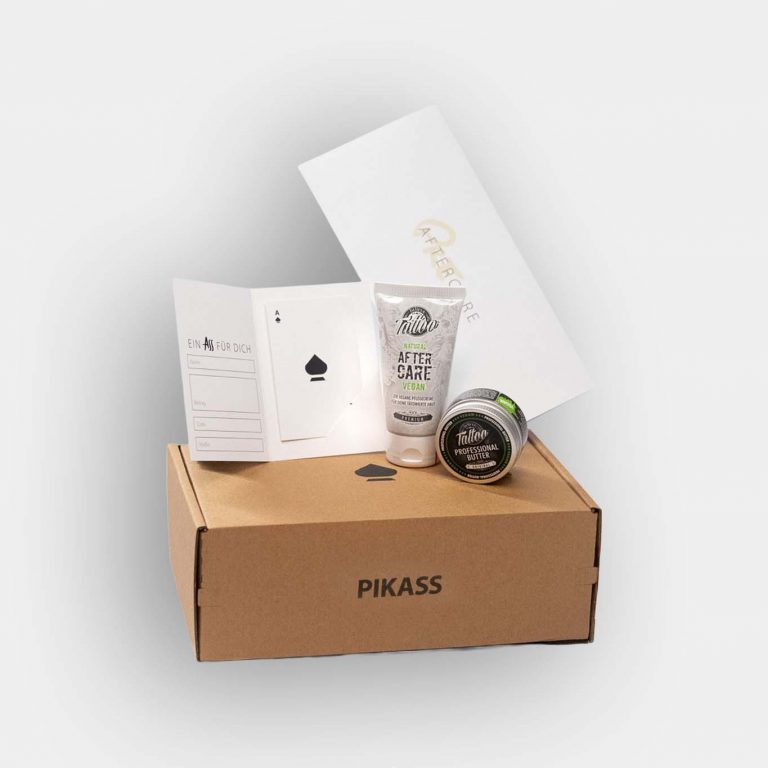 PIKASS Tattoo Geschenkbox S mit Tattoo-Gutschein, Aftercare Guide, Tattoo Butter und Tattoo Pflegecreme auf grauem Hintergrund